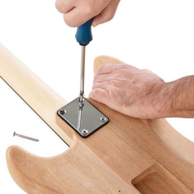 Mão utilizando chave de fendas para fixar placa metálica em guitarra de madeira clara