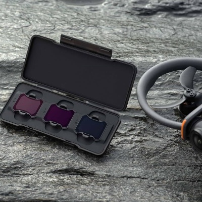 Caixa com filtros coloridos para drone sobre pedra ao lado de drone cinzento