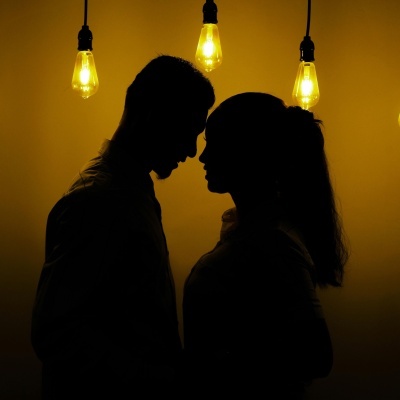Silhueta de casal junto a lâmpadas amarelas suspensas
