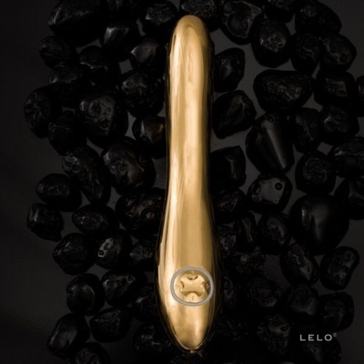 Vibrador dourado sobre pedras pretas com texto LELO®