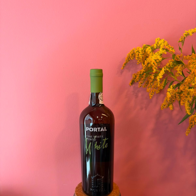Garrafa de vinho Porto com tampa verde e flores amarelas sobre fundo rosa