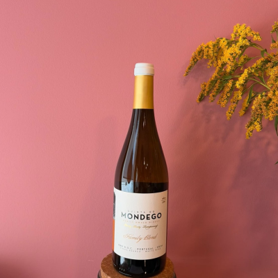 Garrafa de vinho branco Quinta do Mondego com flores amarelas e fundo rosa