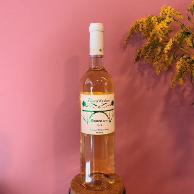 Garrafa de vinho branco Rustik Wisdom com rótulo e flores amarelas ao lado