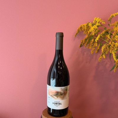 Garrafa de vinho tinto com rótulo Quinta do Portal e flores amarelas, fundo rosa