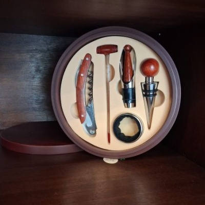 Conjunto de acessórios para vinho em madeira e metal, numa caixa redonda de madeira.