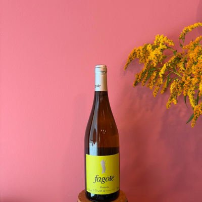 Garrafa de vinho branco com rótulo amarelo e flores amarelas ao lado