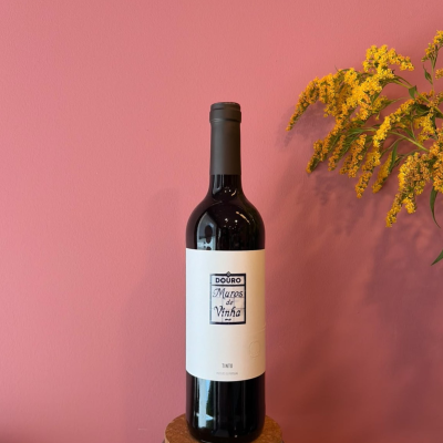 Garrafa de vinho com rótulo branco em fundo rosa e flores amarelas