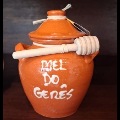 Pote de barro laranja com texto MEL DO GERÊS e colher de pau para mel