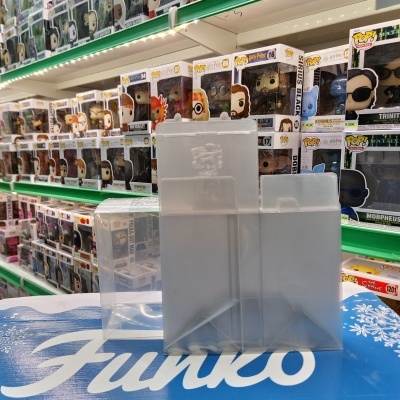 Caixas plásticas transparentes sobre superfície com texto Funko, com prateleiras cheias de bonecos Funko Pop ao fundo