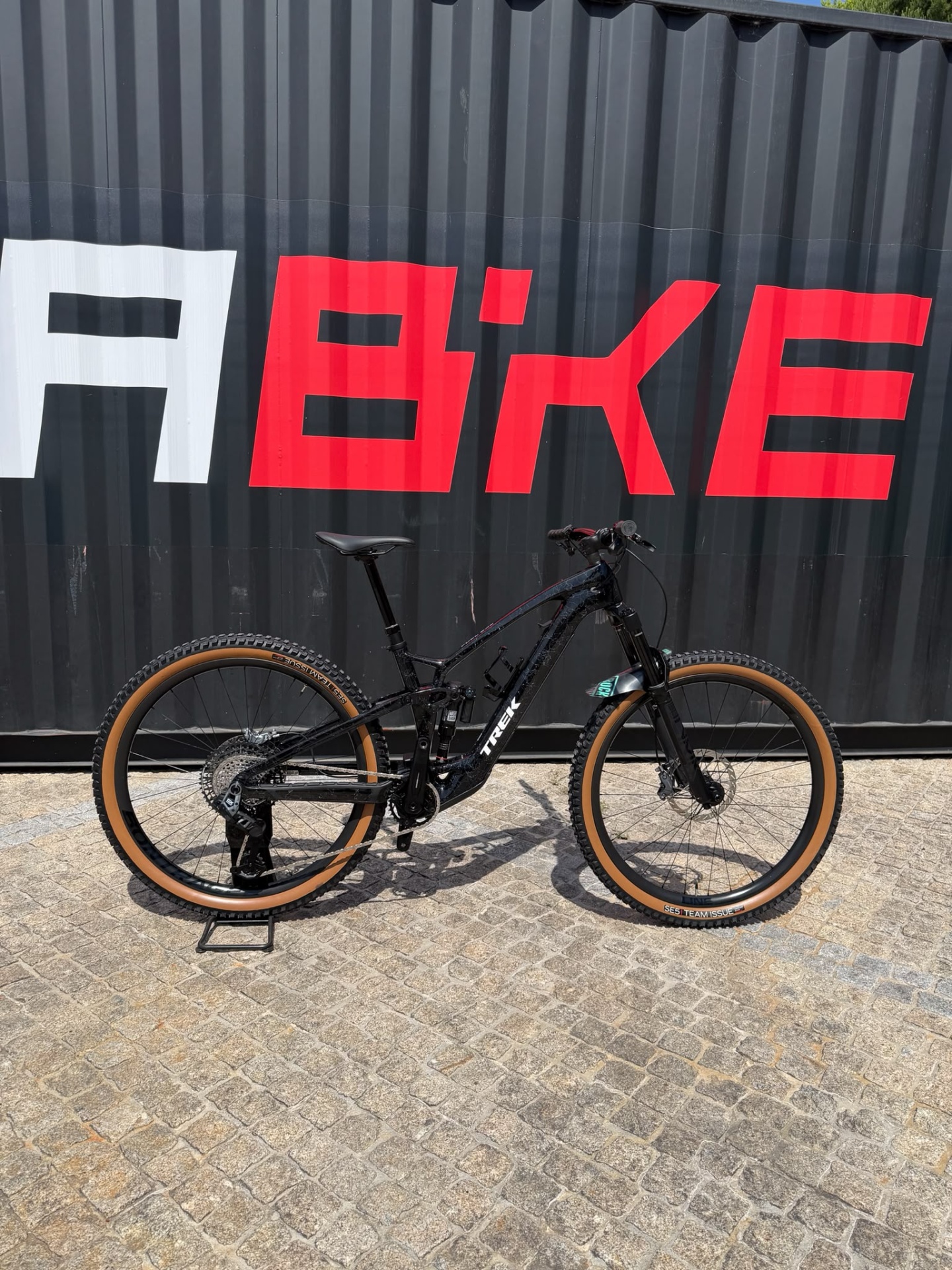 Bicicleta Usada Trek Fuel Exe 9.8 Preto M Bicicleta de montanha preta e castanha junto a parede com letras vermelhas e brancas