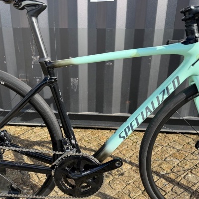 Bicicleta de estrada azul claro e preta com marca SPECIALIZED no quadro