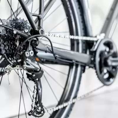 Bicicleta preta com corrente, cassete e desviador traseiro em destaque