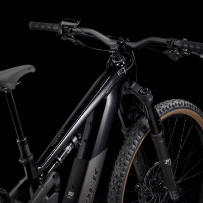 Bicicleta elétrica preta Trek com suspensão dianteira e pneus de cravos em fundo preto