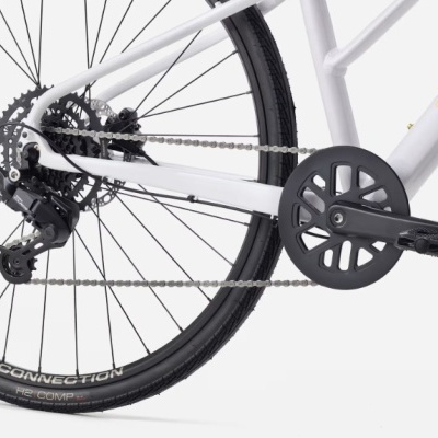 Detalhe da roda traseira e corrente de uma bicicleta branca