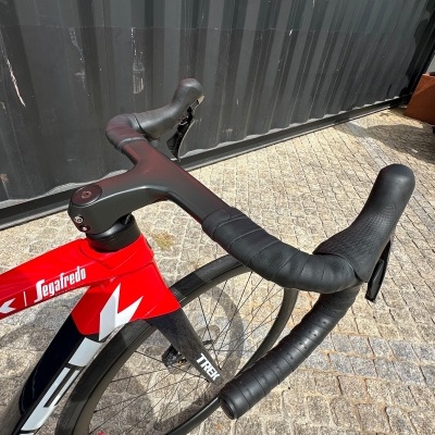 Bicicleta vermelha e preta com guiador preto e pneus perto de contentor preto com letras vermelhas