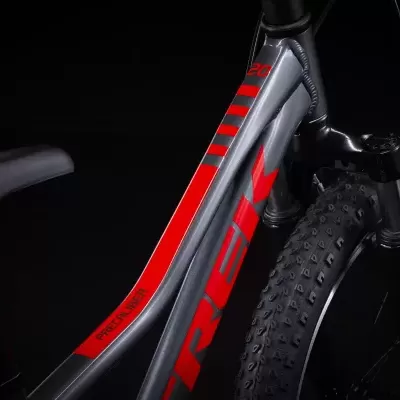 Quadro de bicicleta cinzento e vermelho com texto TREK e MACASKILL, pneus com cravos e selim preto