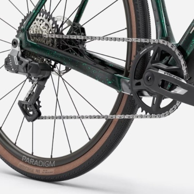 Roda traseira com pneus marrons, corrente e quadro verde escuro de bicicleta