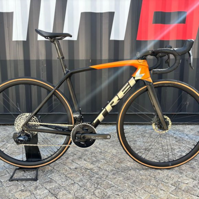 Bicicleta de estrada TREK preta e laranja apoiada em suporte