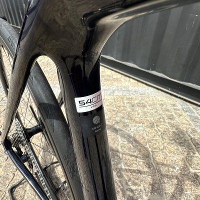 Detalhe de quadro de bicicleta preta com etiquetas e roda traseira