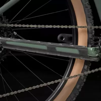 Detalhe da corrente e roda de bicicleta verde com pneus castanho claro.