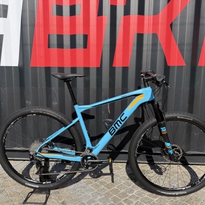 Bicicleta de montanha BMC azul com suporte e fundo de contentor grafitado.
