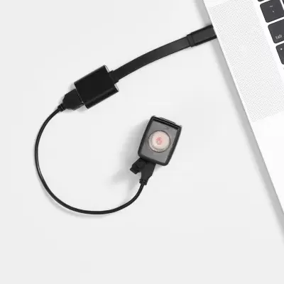 Cabo adaptador USB preto ligado a portátil prateado com dispositivo preto e botão vermelho