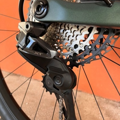 Desviador traseiro de bicicleta DEORE XT e roda com componentes metálicos prateados sobre fundo laranja