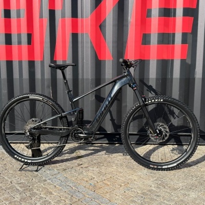 Bicicleta de montanha cinza brilhante contra parede cinzenta com letras vermelhas