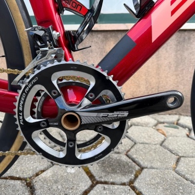 Detalhe do pedal e caixa de pedal de bicicleta vermelha com componente FSA Gossamer preto prateado e corrente dourada