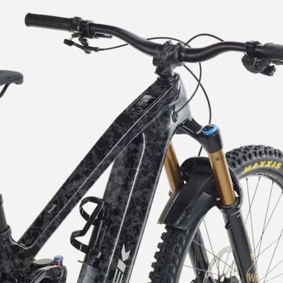 Bicicleta de montanha com quadro preto e padrões texturizados e pneus Maxxis.