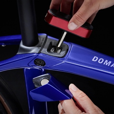 Bicicleta azul DOMANE com compartimento aberto e ferramenta TALLY AERO sendo removida