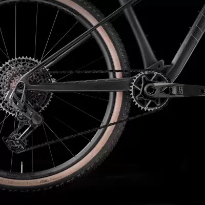 Parte traseira de bicicleta com pneus pretos e bege, corrente e engrenagens visíveis