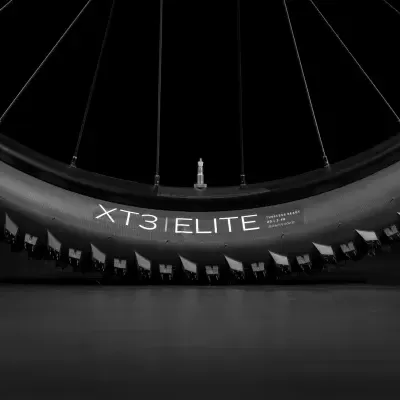 Pneu de bicicleta com o texto XT3 ELITE e válvula no centro da roda