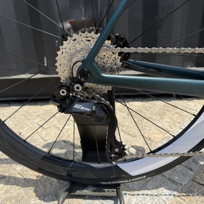 Roda traseira de bicicleta com sistema de mudanças Shimano 105 e corrente metálica.