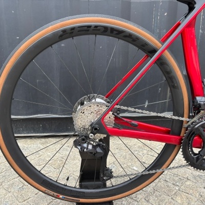 Roda traseira de bicicleta de estrada com pneu castanho e quadro vermelho carbono
