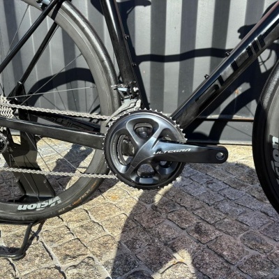 Detalhe de bicicleta preta com sistema ULTEGRA e rodas VISION sobre calçada