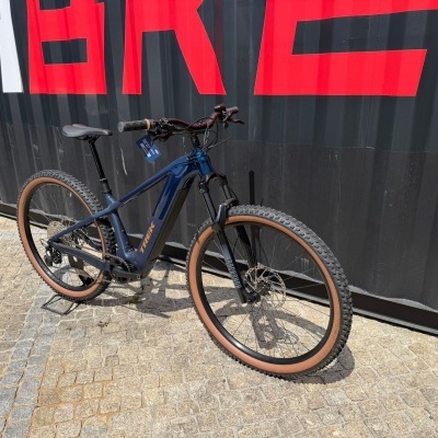 Bicicleta de montanha elétrica Trek azul encostada a um contentor