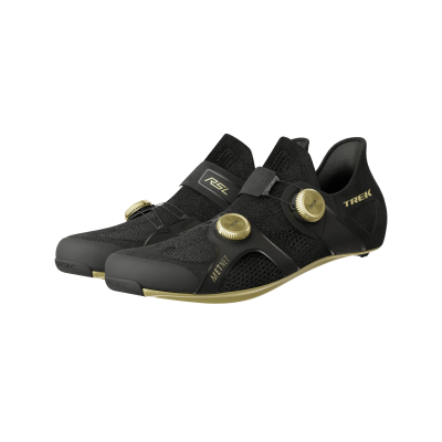 Sapatilhas pretas com disco de ajuste dourado e textos TREK e MET nas laterais