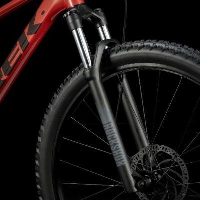 Bicicleta montanha vermelha com suspensão dianteira preta e roda com disco de travão