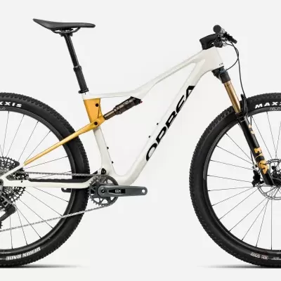 Bicicleta de montanha full suspension branca e dourada com pneus Maxxis