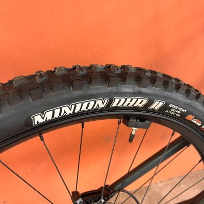 Pneu preto de bicicleta MINION DHR II com detalhes brancos num fundo laranja