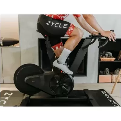 Bicicleta estática preta com ciclista em roupa preta e vermelha, dentro de casa