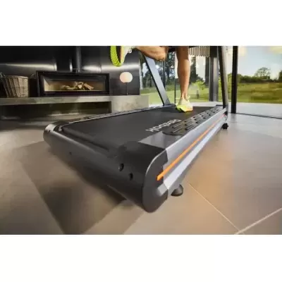 Tapete rolante Reebok preto com detalhes cinza e laranja em uso num ambiente interior