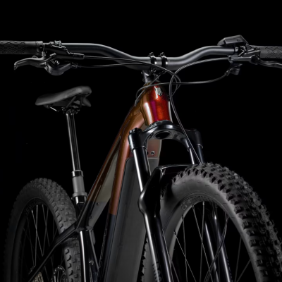 Bicicleta elétrica de montanha cobre e preta com pneus grossos sobre fundo preto