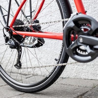 Detalhe da roda traseira e componentes de bicicleta vermelha contra parede clara