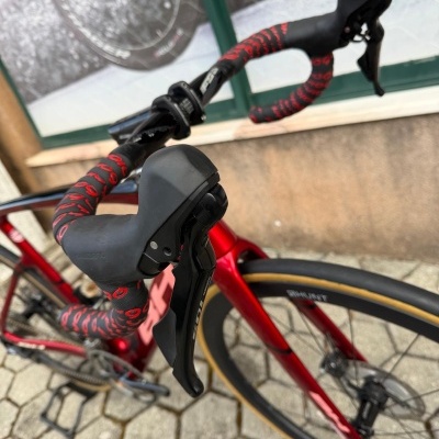 Bicicleta de estrada vermelha com punhos curvos e manetes pretas