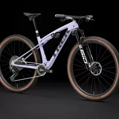 Bicicleta de montanha lilás com pneus castanhos e componentes pretos