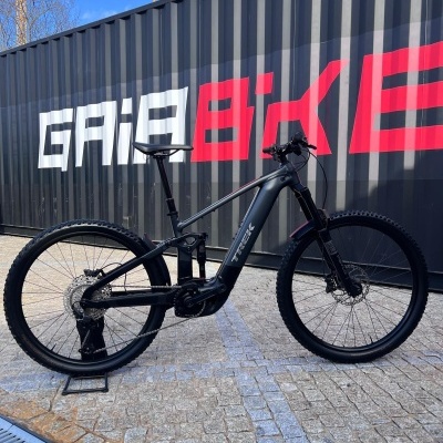 Bicicleta elétrica de montanha preta TREK com suspensão dianteira RockShox e motor integrado perto de contentor GAIABIKE
