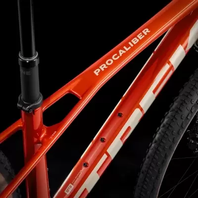 Bicicleta laranja com texto PROCALIBER e TREK em fundo preto