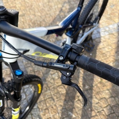 Punho de bicicleta preto com manete Shimano e quadro azul e branco com texto amarelo OPPA